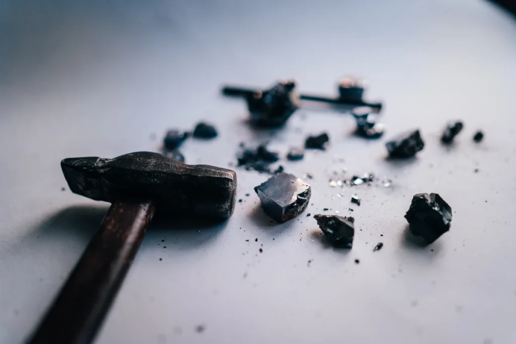 Stop Stress Shaming Yourself to Save Your Life Hammer beside broken mineral fragments representing the power of one small action to break through stress