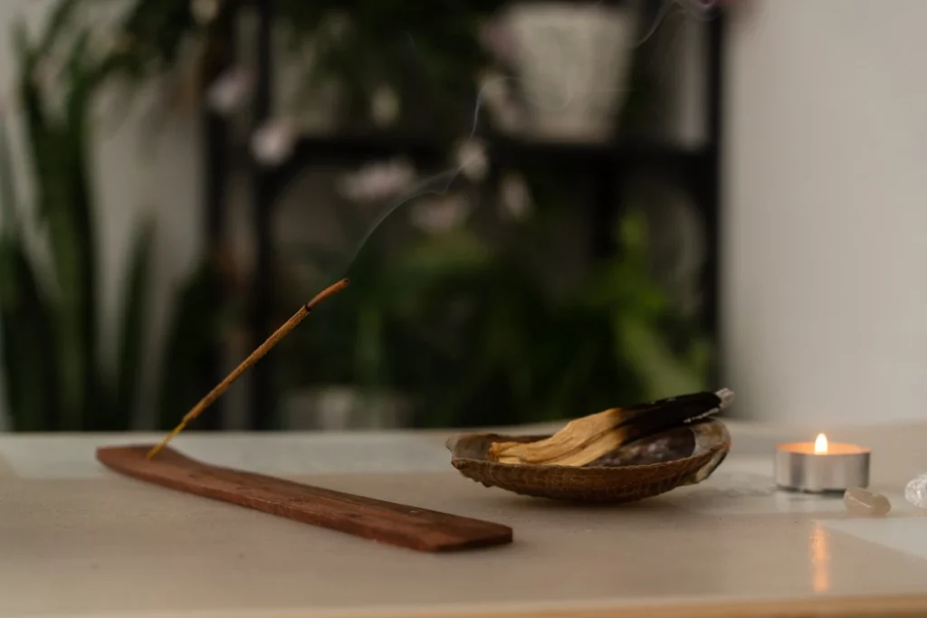 Incense stick and palo santo with a candle on a calm surface representing meditation and mindfulness