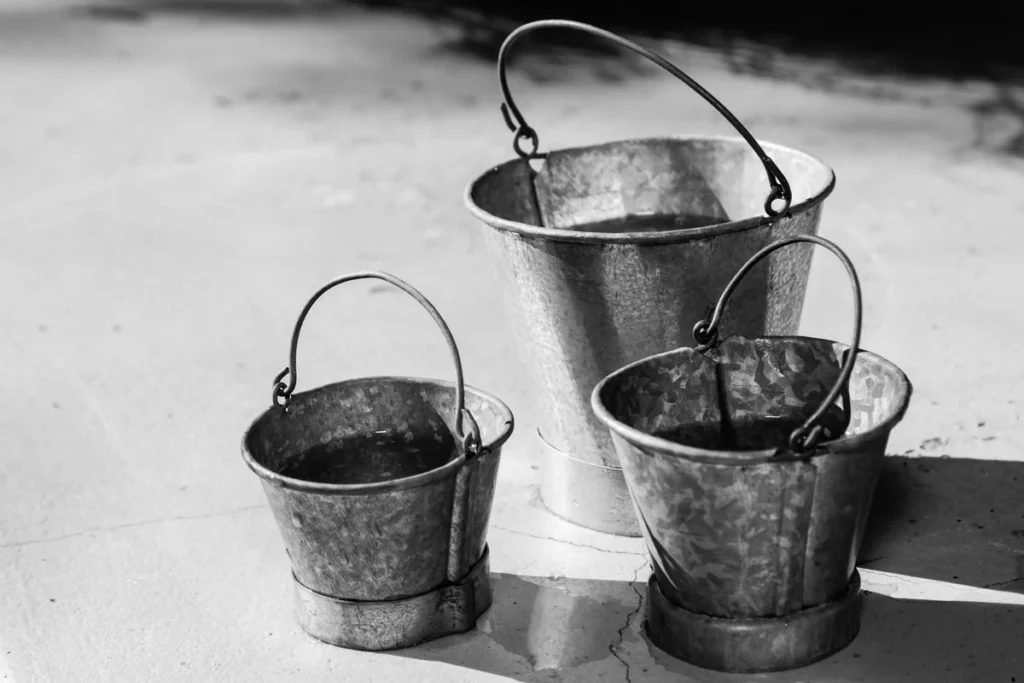 Three galvanized metal buckets in graduated sizes representing the three-bucket system for understanding stress