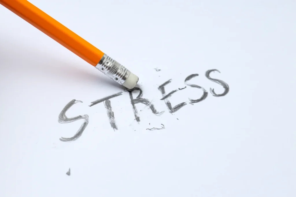 A Tiny Tactic to Reduce Stress Fast in a Big Way Pencil erasing the word stress on white paper representing the need to stop shaming ourselves about stress