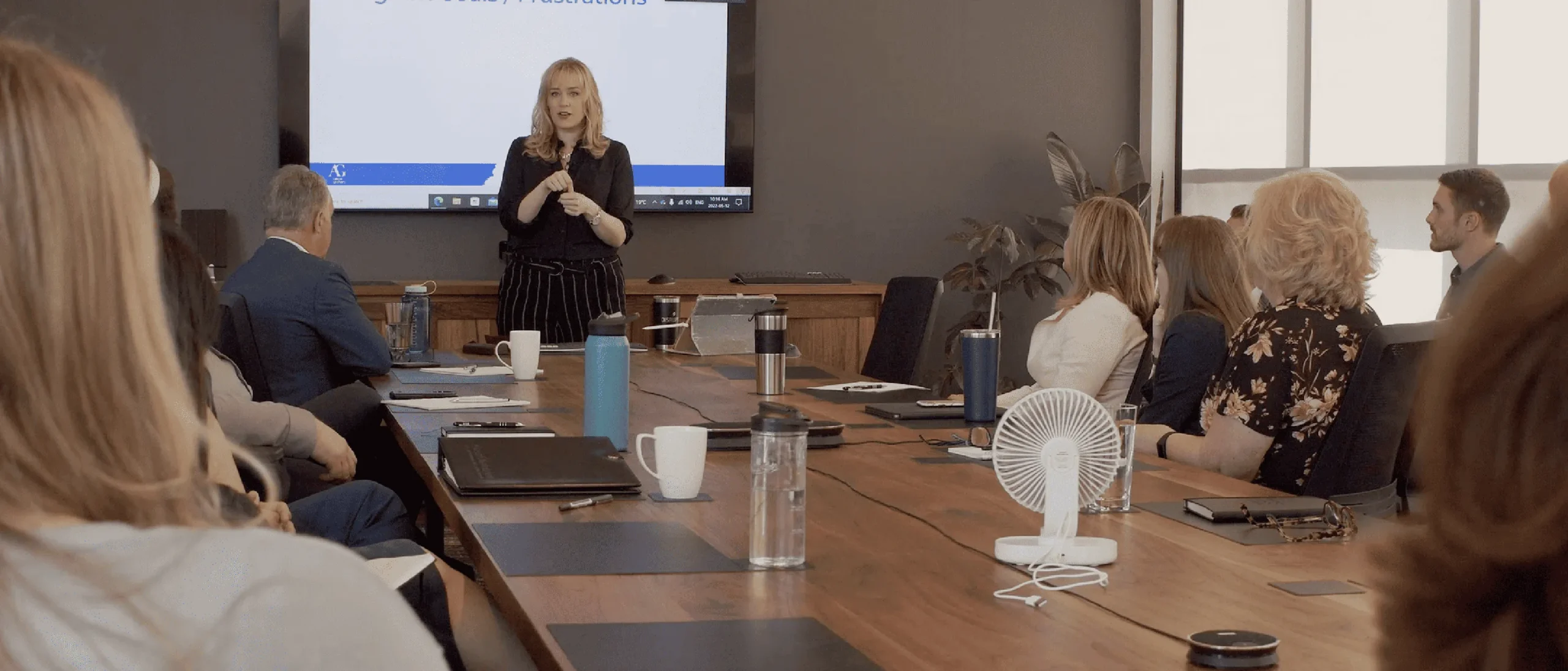 allison graham standing as she teaches an engaged group of professionals who are sitting around a boardroom table