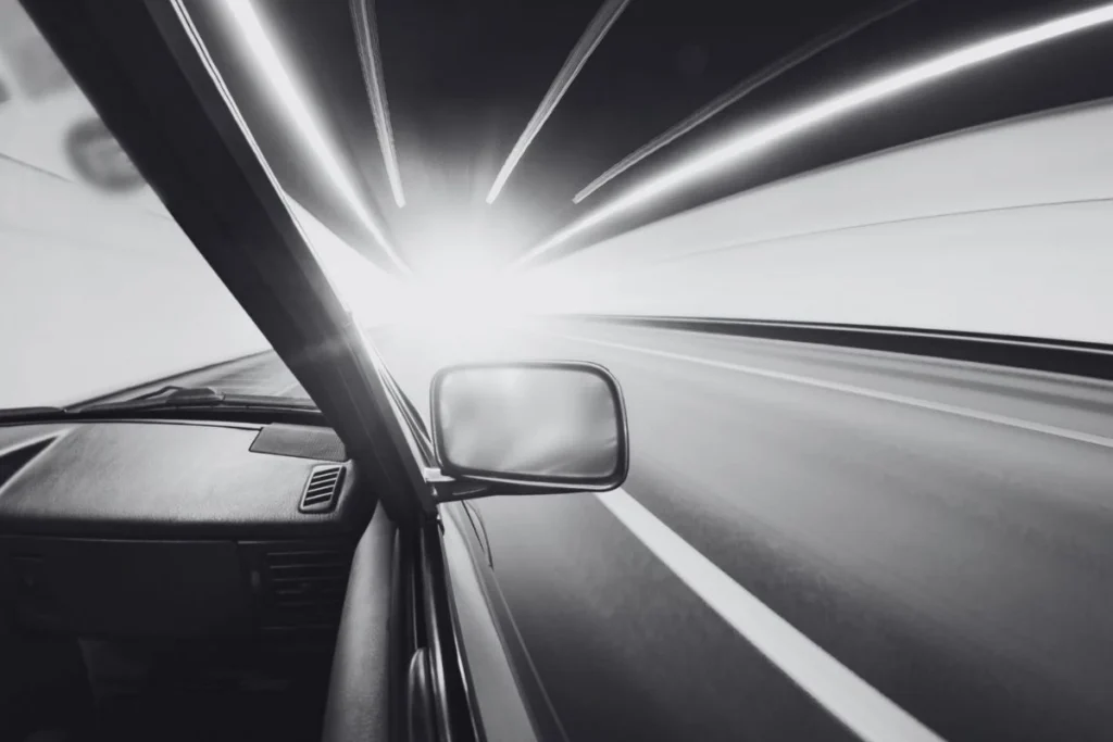 Speeding car with motion-blurred city lights seen from the driver's perspective representing the lie that things will slow down